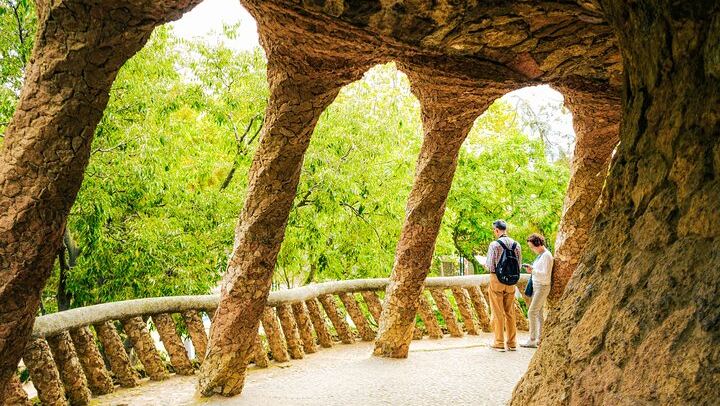 Camina por debajo de las columnas de piedra de Gaudí en Park Güell, donde la arquitectura y la naturaleza se funden a la perfección.