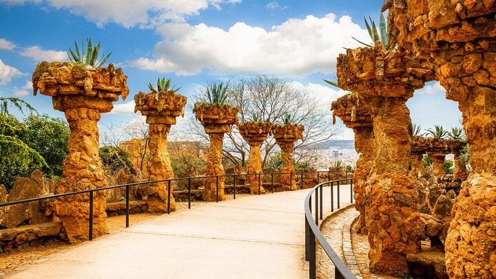 Descubre los caminos sinuosos y las columnas de piedra del Park Güell, que muestran la armonía de Gaudí con la naturaleza.