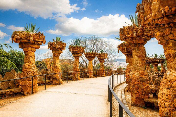 Descubre los caminos sinuosos y las columnas de piedra del Park Güell, que muestran la armonía de Gaudí con la naturaleza.