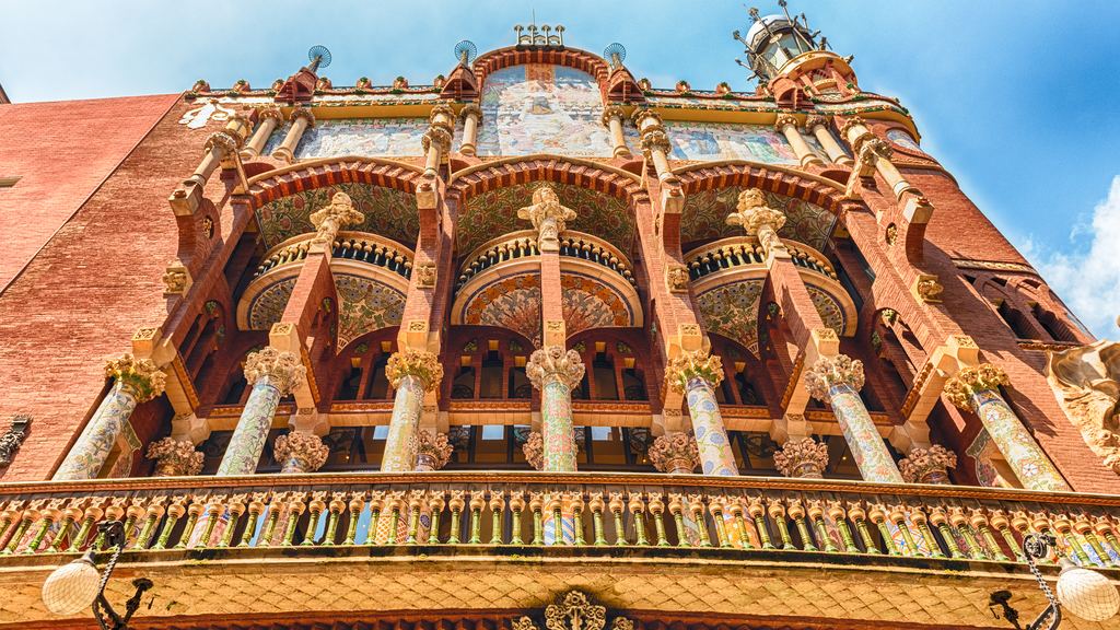 The facade of the Palau de la Música Catalana, featuring brick and mosaic work, with its columned balcony and the sign for the Orfeó Català