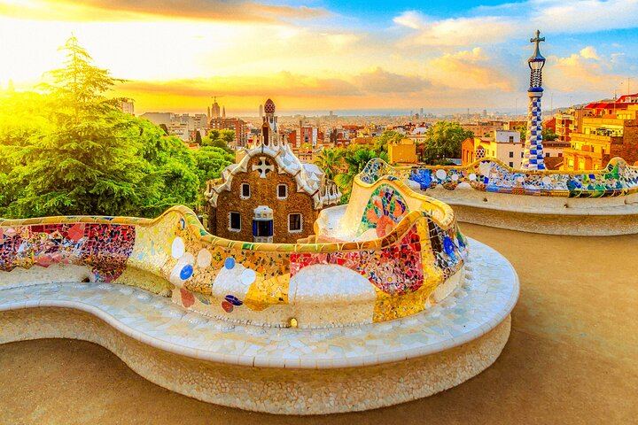 Relájese en el famoso banco serpenteante del Park Güell, enmarcado por vibrantes mosaicos y el horizonte de Barcelona.